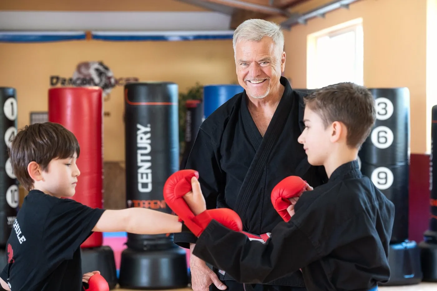 Andreas Busche zeigt zwei Kindern eine Schlagtechnik mit Boxhandschuhen